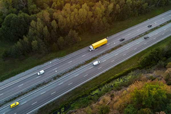 Lastbilar ovanifrån på en bilväg med grönska runtomkring